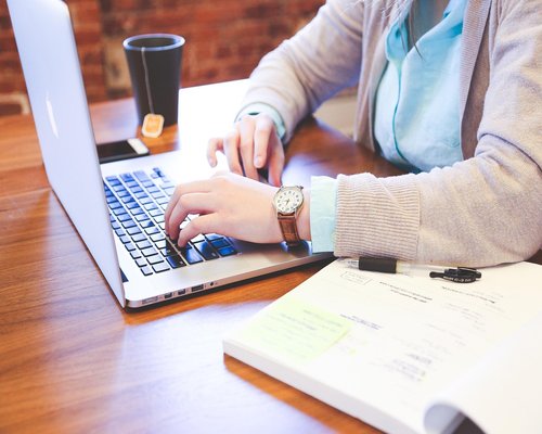 A person typing responsibly on a professional keyboard inside a bright room